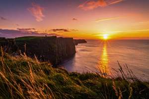 Luce dorata del tramonto che illumina l'orizzonte e le scogliere sull'Oceano Atlantico nel 2026